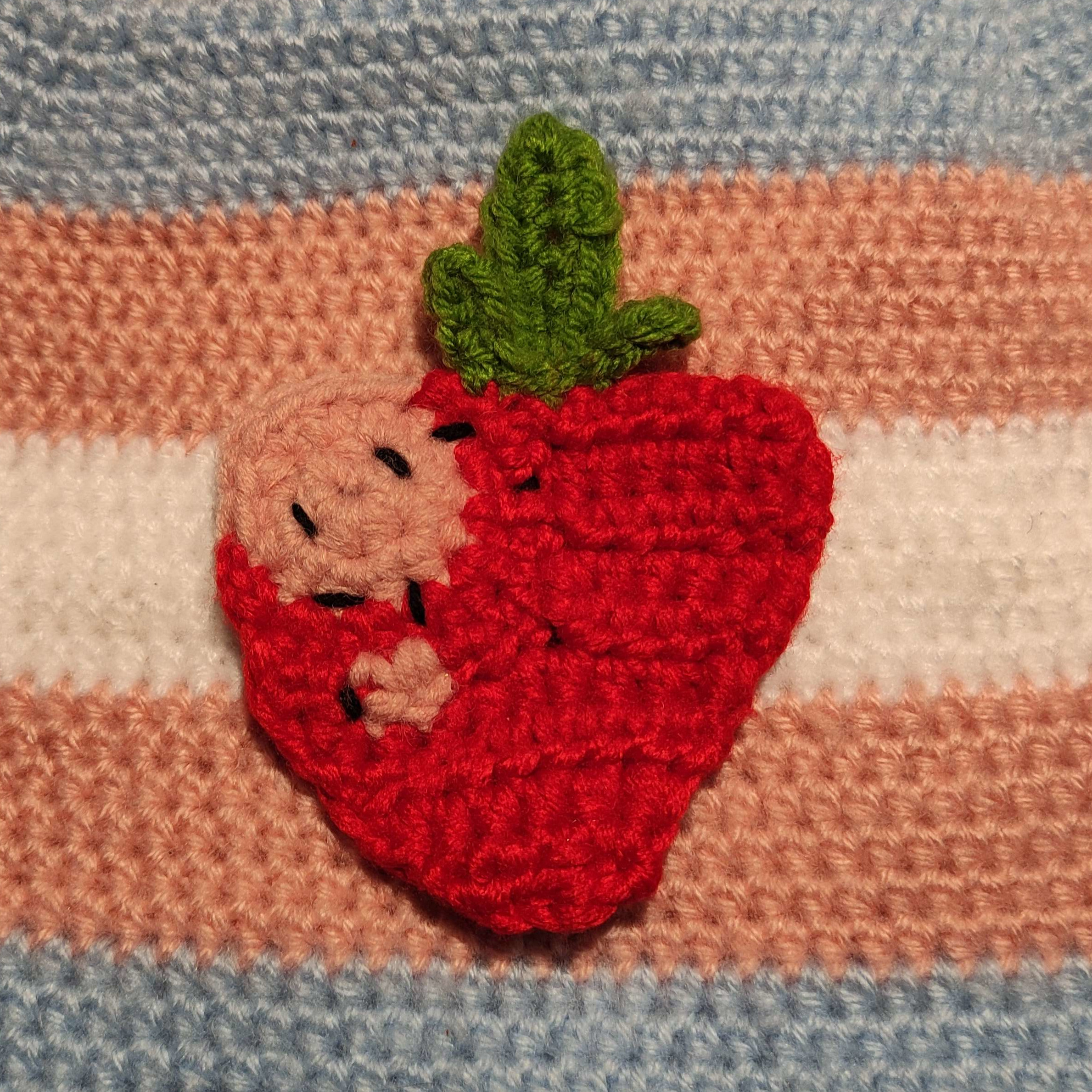 My profile picture: a strawberry on a trans flag, both made out of wool